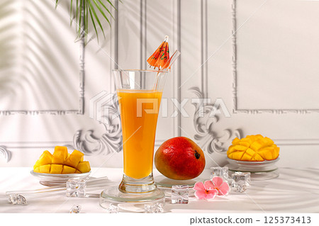 Homemade cocktail, juice or lemonade with mango slices and ice on sunny kitchen table.Summer party concept and Detox diet,Modern still life with tropical fruits.Restaurant menu 125373413