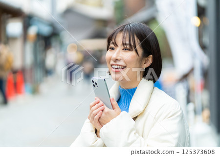 一位婦女正在欣賞老式的街景；一位穿著外套旅行的女人；獨自旅行 125373608