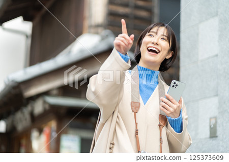 A woman looking at the old-fashioned streetscape; A woman in a coat traveling; Traveling alone A woman looking at the old-fashioned streetscape; A woman in a coat traveling; Traveling alone 125373609