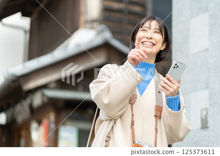 A woman looking at the old-fashioned streetscape; A woman in a coat traveling; Traveling alone A woman looking at the old-fashioned streetscape; A woman in a coat traveling; Traveling alone 125373611