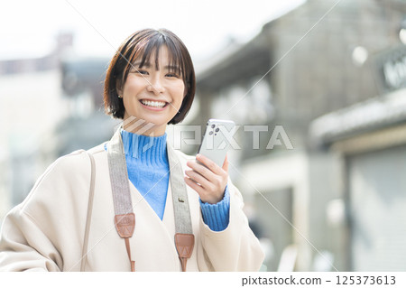 一位婦女正在欣賞老式的街景；一位穿著外套旅行的女人；獨自旅行 125373613