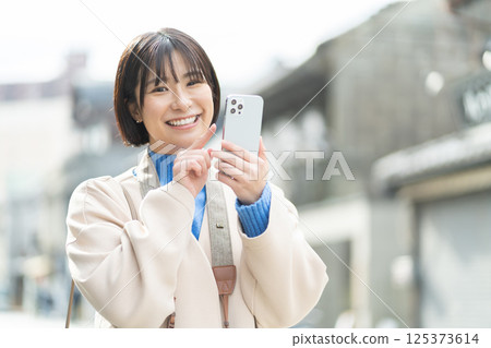 一位婦女正在欣賞老式的街景;一位穿著外套旅行的女人;獨自旅行 一位婦女正在欣賞老式的街景;一位穿著外套旅行的女人;獨自旅行 125373614