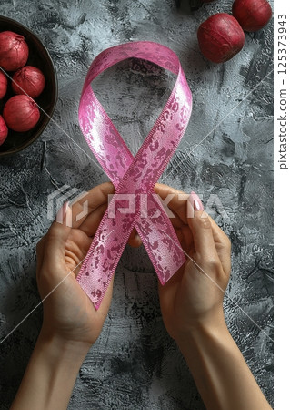 Close-up of hands holding a pink ribbon symbolizing awareness and hope Close-up of hands holding a pink ribbon symbolizing awareness and hope 125373943