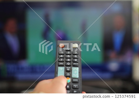 A person with a TV remote controls the remote control to switch channels to watch TV shows. 125374591