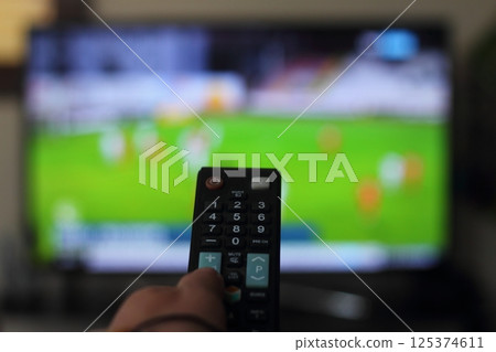 A person with a TV remote controls the remote control to switch channels to watch TV shows. 125374611