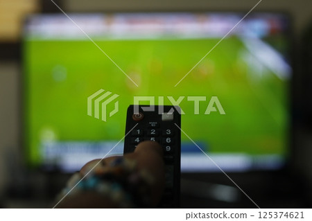 A person with a TV remote controls the remote control to switch channels to watch TV shows. A person with a TV remote controls the remote control to switch channels to watch TV shows. 125374621