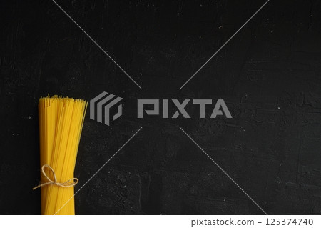 flat lay of spaghetti for cooking italian pasta over black background 125374740