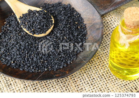 Black cumin seeds and essential oil with bowl and wooden shovel or spoon. Nigella Sativa 125374793