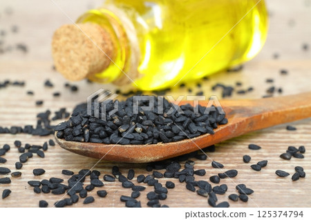 Black cumin seeds and essential oil with bowl and wooden shovel or spoon. Nigella Sativa 125374794