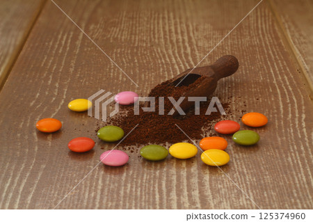 multi-colored candy and roasted coffee beans on brown background. With wooden spoon. 125374960
