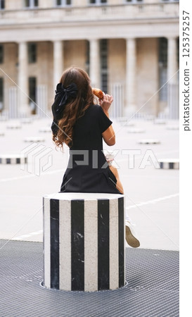 Morning coffee and croissant in French courtyard with elegant woman in black 125375257