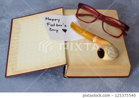 Happy Fathers day concept with pipe, glasses and books over wooden background Happy Fathers day concept with pipe, glasses and books over wooden background 125375540