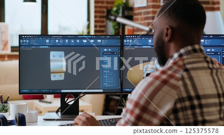 African american designer uses 3D modeling tools and CAD software for industrial projects. Working on creating prototypes and gears models for the manufacturing industry. Camera B. 125375578