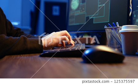 Meticulous hacker typing on computer keyboard, doing data breaches and financial theft in dark bunker. Close up shot on cybercriminal stealing users bank account credentials, camera A 125375597