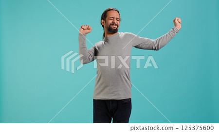 Portrait of man stretching his body, experiencing fatigue and tension in muscles. Tired person with sprained ligaments stretching limbs to relieve stress, studio background, camera A 125375600