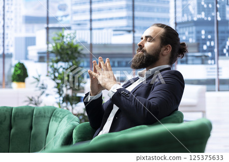 Determined young CEO focuses on tranquility using sound therapy to clear his mind, reduce stress in the office. Dedication to wellness ensures success within the business industry. 125375633