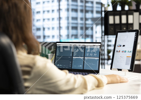 Business leader and trader searching for a new investment solution, examining trading risks and opportunities for company development. Female CEO planning finances and doing research. Business leader and trader searching for a new investment solution, examining trading risks and opportunities for company development. Female CEO planning finances and doing research. 125375669