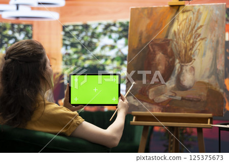 Painter admiring her creative masterpiece in art studio next to green screen, finishing her oil paint mixed with watercolor artwork. Creative artist enjoying quality time in her atelier. Painter admiring her creative masterpiece in art studio next to green screen, finishing her oil paint mixed with watercolor artwork. Creative artist enjoying quality time in her atelier. 125375673