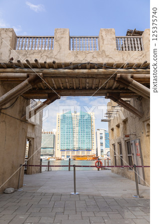 Old town in Al Seef Cultural Historical District on shores of Dubai Creek. Tourist place with old streets, houses and shops, Dubai, UAE. Vertical photo 125375740