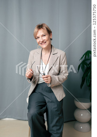 Happy woman. Confident, successful mature woman on light gray background. Looking at camera. High quality photo Happy woman. Confident, successful mature woman on light gray background. Looking at camera. High quality photo 125375750