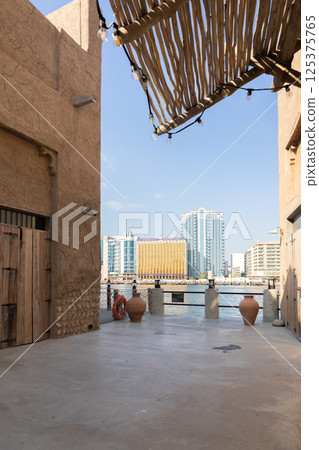 Old town in Al Seef Cultural Historical District on shores of Dubai Creek. Tourist place with old streets, houses and shops, Dubai, UAE. Vertical photo Old town in Al Seef Cultural Historical District on shores of Dubai Creek. Tourist place with old streets, houses and shops, Dubai, UAE. Vertical photo 125375765
