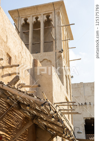 Old town in Al Seef Cultural Historical District on shores of Dubai Creek. Tourist place with old streets, houses and shops, Dubai, UAE. Vertical photo 125375769