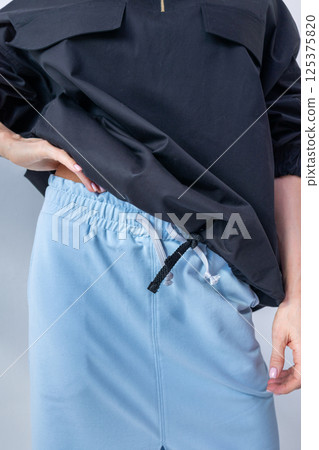 Close-up of black windbreaker jacket and light blue skirt on white background. Fashionable female style. Studio photography. Vertical photo. High quality photo Close-up of black windbreaker jacket and light blue skirt on white background. Fashionable female style. Studio photography. Vertical photo. High quality photo 125375820