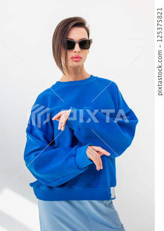 Elegant woman in blue sweatshirt and light blue skirt on white background. Fashionable female style. Studio photography. Vertical photo. High quality photo Elegant woman in blue sweatshirt and light blue skirt on white background. Fashionable female style. Studio photography. Vertical photo. High quality photo 125375821