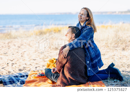 Loving couple walks on beach along sea on sunny autumn day. Weekend and lifestyle concept. High quality photo 125375827