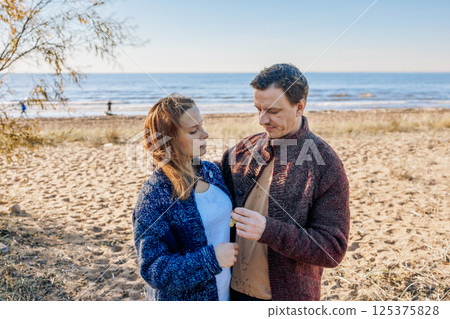 Loving couple walks on beach along sea on sunny autumn day. Weekend and lifestyle concept. High quality photo 125375828
