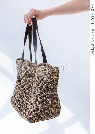 Female hand holding fashionable woven bag. Fashion and luxury accessories. Vertical photo. High quality photo Female hand holding fashionable woven bag. Fashion and luxury accessories. Vertical photo. High quality photo 125375876