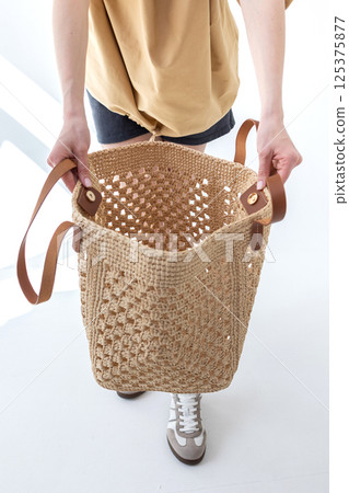 Female hand holding fashionable woven bag. Fashion and luxury accessories. Vertical photo. High quality photo 125375877