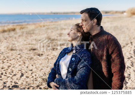 Loving couple walks on beach along sea on sunny autumn day. Weekend and lifestyle concept. High quality photo 125375885