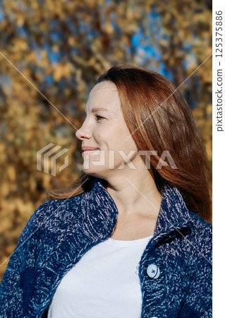 Female portrait. Beautiful young girl with long dark hair on a sunny autumn day outdoors. Vertical photo. High quality photo 125375886