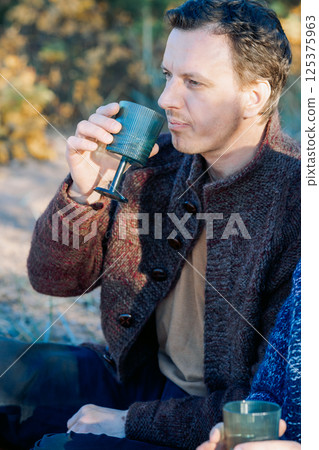 Male portrait. Beautiful young man with long dark hair on a sunny autumn day outdoors. Vertical photo. High quality photo 125375963
