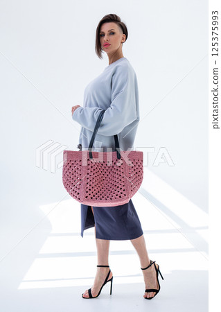 Female holding fashionable pink woven bag. Fashion and luxury accessories. Bottom view. Vertical photo. High quality photo 125375993