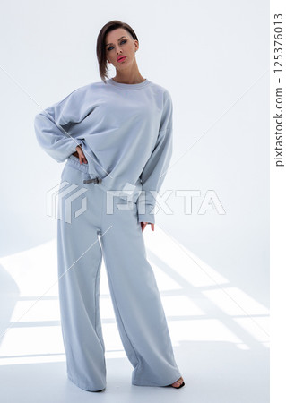 Young woman in gray sweatshirt and pants on white background. Studio photography. Vertical photo. High quality photo Young woman in gray sweatshirt and pants on white background. Studio photography. Vertical photo. High quality photo 125376013