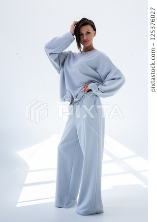 Young woman in gray sweatshirt and pants on white background. Studio photography. Vertical photo. High quality photo 125376027