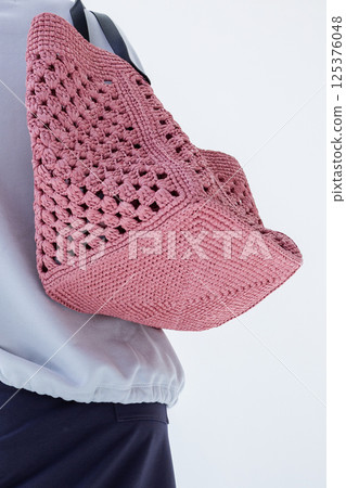 Female hand holding fashionable pink woven bag. Fashion and luxury accessories. Bottom view. Vertical photo. High quality photo 125376048