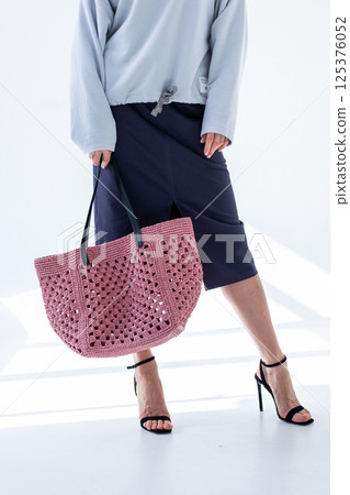 Female hand holding fashionable pink woven bag. Fashion and luxury accessories. Vertical photo. High quality photo 125376052