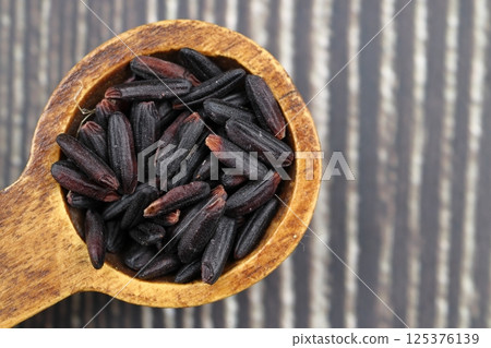 Black wild rice with bamboo spoon on wooden background Black wild rice with bamboo spoon on wooden background 125376139