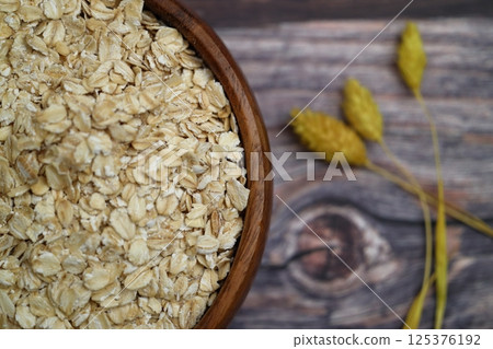 Oat flakes uncooked in a brown bowl on wooden table. Healthy food for breakfast 125376192