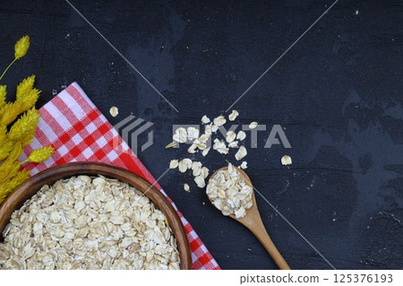 Oat flakes uncooked in a brown bowl on wooden table. Healthy food for breakfast 125376193