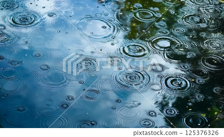 雨滴映照在藍色的水面上 / 讓人感受到大自然的寧靜和水波蕩漾的背景素材 125376326