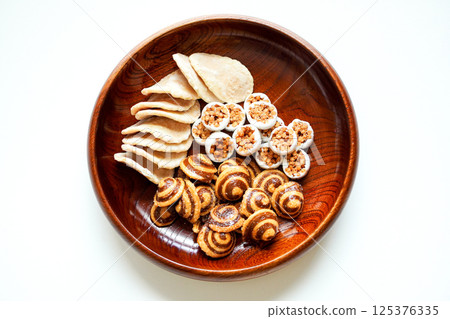 Aerial view of Japanese sweets (tea snacks) such as karinto and ginger rice crackers served on a wooden plate Aerial view of Japanese sweets (tea snacks) such as karinto and ginger rice crackers served on a wooden plate 125376335