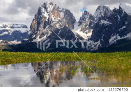 Majestic mountain landscape with snow-capped peaks and reflective puddle in spring near Valley of Funes at Dolomites, Italy 125376790