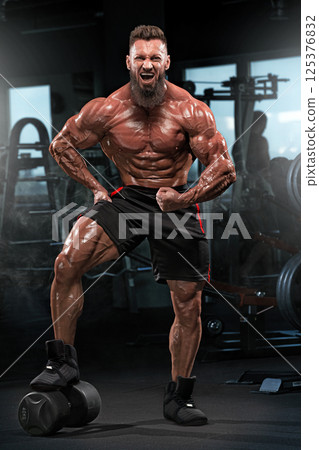 muscular individual performs confident pose in fitness studio highlighting his impressive physique. 125376832
