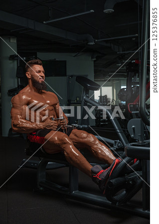 muscular man performs workout on rowing machine in modern gym setting. focus is on his effort and dedication improving physical fitness and strength. muscular man performs workout on rowing machine in modern gym setting. focus is on his effort and dedication improving physical fitness and strength. 125376855
