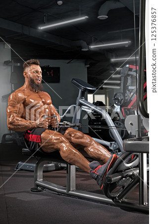 muscular individual performs seated row exercise showcasing strength and determination. gym features modern equipment and motivating atmosphere ideal for fitness enthusiasts. muscular individual performs seated row exercise showcasing strength and determination. gym features modern equipment and motivating atmosphere ideal for fitness enthusiasts. 125376857