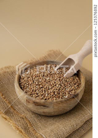Raw buckwheat porridge in neutral beige background copy space. Whole spelt grain species. High protein fiber-rich vegan plant based food ingredient. Gluten free superfood healthy nutritional dietary 125376892